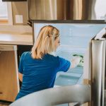 woman cleaning the inside of a fridge
