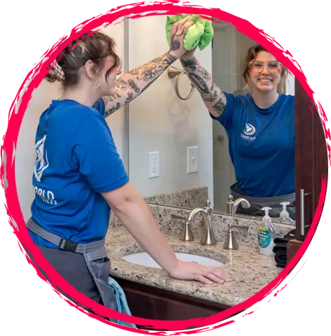 A professional cleaner wiping a restroom mirror